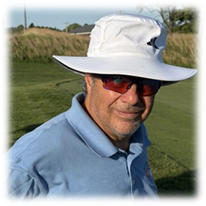 The image shows a person wearing a white hat and a blue polo shirt, standing on a green grassy field under a clear sky.

AI-generated content may be incorrect.